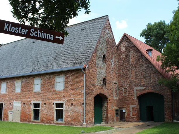 Kloster Schinna Historisches Backsteingebäude des Klosters Schinna mit grünen Türen und malerischem Baum im Vordergrund.