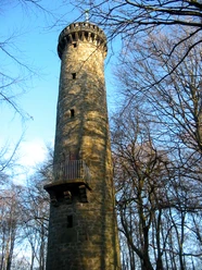 Wilhelmsturm Der Wilhelmsturm erhebt sich majestätisch aus einem bewaldeten Umfeld und strahlt in der Sonne.