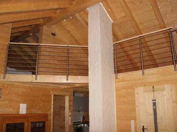 Ferienhaus Breibach Geräumiges Chalet-Interieur mit Holzvertäfelung, Zwischengeschoss und moderner Metallbalustrade.