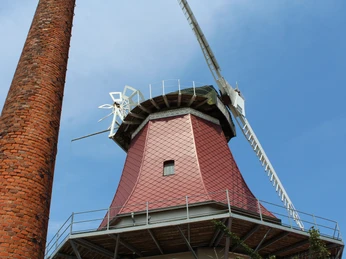 Gallerieholländerwindmühle Emtinghausen Rote Gallerieholländerwindmühle mit markantem Ziegelstein-Kamin vor klarem blauen Himmel in Emtinghausen.