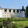 Schloß Neuhaus mit Barockgarten (Sommerbepflanzung) Schloss Neuhaus mit barockem Garten im Vordergrund, Sommerblumen blühen, blauer Himmel im Hintergrund.