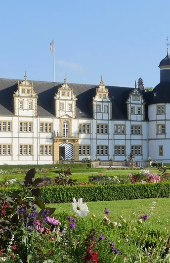 Schloß Neuhaus mit Barockgarten (Sommerbepflanzung) Schloss Neuhaus mit barockem Garten im Vordergrund, Sommerblumen blühen, blauer Himmel im Hintergrund.