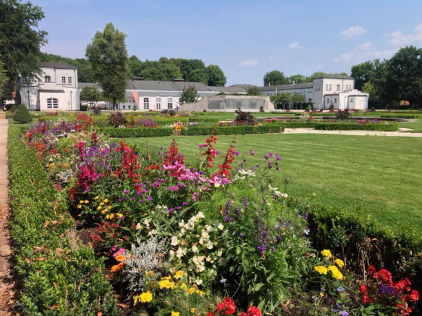 Blumenbeete vor dem barocken Brunnentheater und der Schlosshalle, eingebettet in eine gepflegte Gartenanlage.