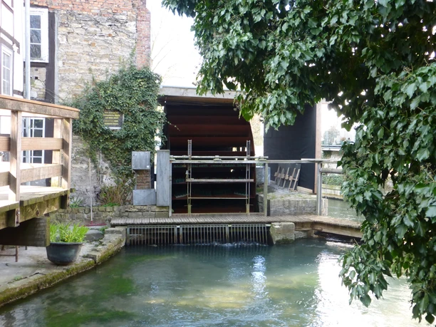 Stümpelsche Mühle Ansicht eines historischen Mühlengebäudes mit Wasserrad, umgeben von üppigem Grün und fließendem Wasser.