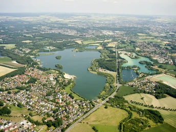 Luftaufnahme von Paderborn-Sande mit dem Lippesee, umgeben von grünen Feldern und Siedlungen.