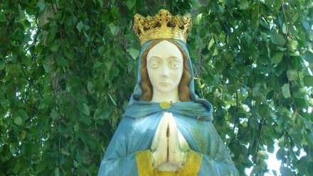Marienstatue am "Stern", Haxtergrund bei Paderborn Marienstatue mit goldener Krone und betenden Händen, umgeben von grünem Blätterwerk im Haxtergrund.