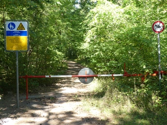 Fußgänger und Wanderer erlaubt! Waldweg mit Schranke und Schildern. Fußgänger erlaubt, Radfahren verboten. Dicht bewachsene Umgebung.