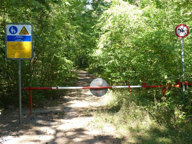 Fußgänger und Wanderer erlaubt! Waldweg mit Schranke und Schildern. Fußgänger erlaubt, Radfahren verboten. Dicht bewachsene Umgebung.