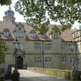 Wasserschloss Ulenburg umgeben von Bäumen, mit Brücke zum Eingang und markanten Türmen.