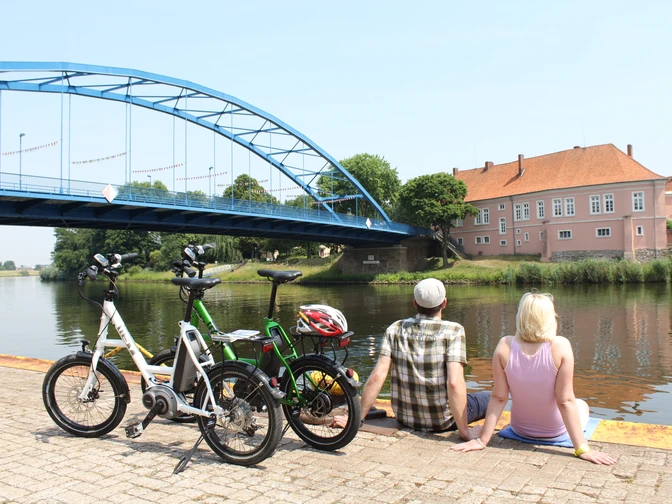Grafenschloss zu Hoya Ein Paar sitzt entspannt am Wasser, mit Blick auf das historische Grafenschloss zu Hoya und eine blaue Brücke.A couple sits relaxed by the water, with a view of the historic Hoya Castle and a blue bridge.Et par sidder afslappet ved vandet med udsigt til det historiske Hoya-slot og en blå bro.Een koppel zit ontspannen aan het water, met uitzicht op het historische Hoya Kasteel en een blauwe brug.