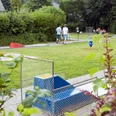 Minigolfplatz mit Rasenbahnen, Spielern und gemütlicher Gartenatmosphäre im Grünen umgeben.