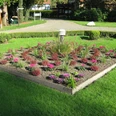 Kurwanderweg Ein gepflegtes, quadratisches Blumenbeet mit bunten Pflanzen in einem Park, umgeben von Rasen.