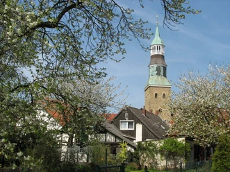 St. Sylvesterkirche.jpg Flowering trees frame a rustic church tower with red-roofed houses in the background.
