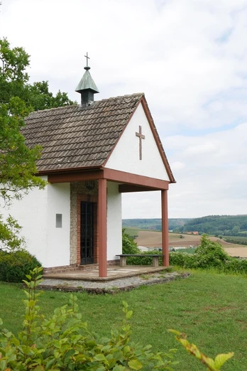 Heimkehrerkapelle Istrup Die Heimkehrerkapelle Istrup steht auf einer grünen Wiese mit Blick auf das hügelige Umland.