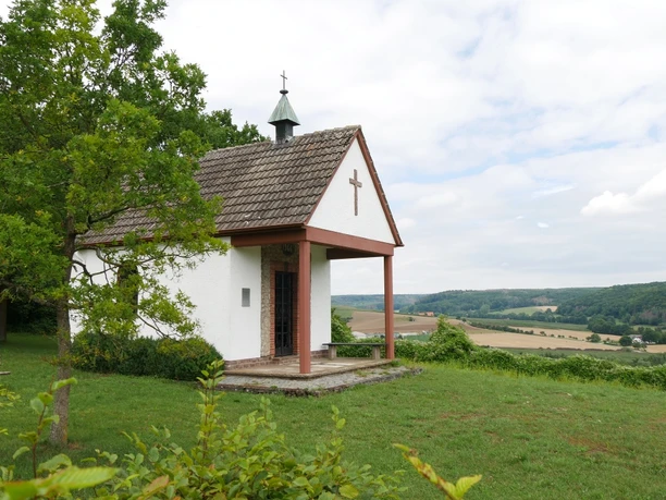 Heimkehrerkapelle Istrup Die Heimkehrerkapelle Istrup steht auf einer grünen Wiese mit Blick auf das hügelige Umland.