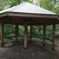 Wanderpilz Ein hölzerner Pavillon im Wald bietet Wanderern einen überdachten Rastplatz mit Sitzmöglichkeiten.