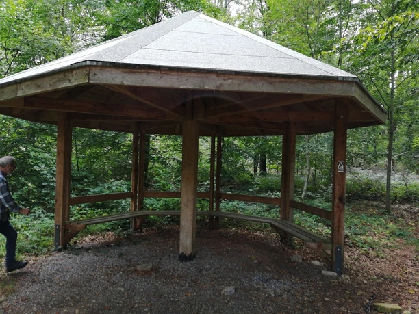 Wanderpilz Ein hölzerner Pavillon im Wald bietet Wanderern einen überdachten Rastplatz mit Sitzmöglichkeiten.