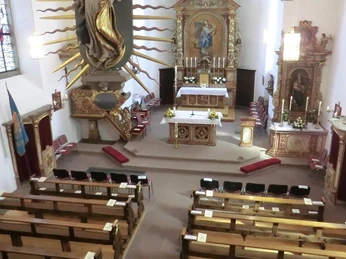 Pfarrkirche St. Bartholomäus mit dem Barockaltar Blick in eine Kirche mit prunkvollem Barockaltar, flankiert von reich verzierten Heiligenfiguren.