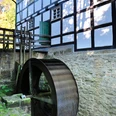 Gutswassermühle Hudenbeck Historische Wassermühle Hudenbeck mit beeindruckendem Fachwerk und rotierendem Wasserrad im Grünen.