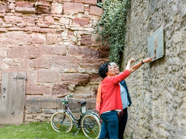 Diekturm Zwei Personen schauen sich ein Hinweisschild vor dem Diekturm an.