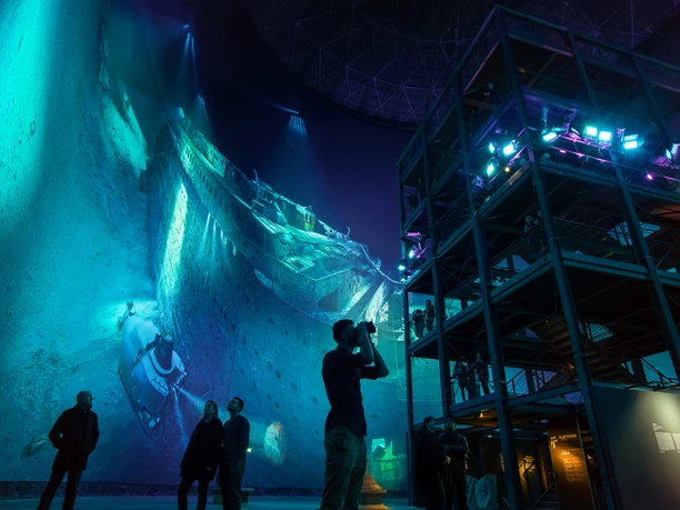 asisi Panometer Leipzig Menschen betrachten ein großes, beleuchtetes Panoramabild einer untergegangenen Titanic.