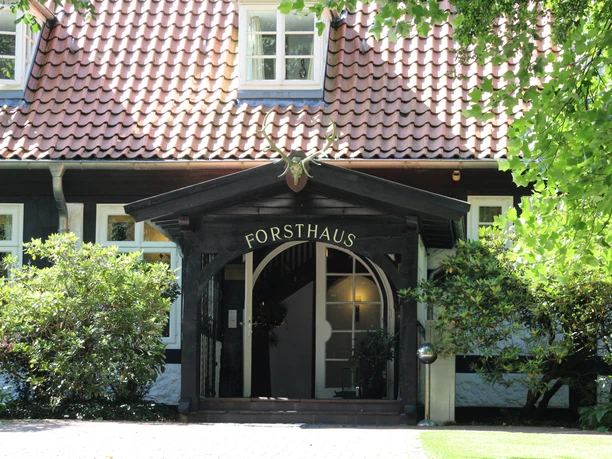 Bruchhausen-Vilsen Forsthaus Heiligenberg Eingang eines traditionellen Forsthauses mit Rotdach und Hirschgeweih über dem Eingangstor.