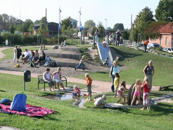 Auf einem belebten Wasserspielplatz entdecken Kinder vergnügt die Wasserpumpen und kleinen Bäche.