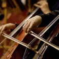 WW_NWD_Konzert_Hoexter.jpg Musiker spielt leidenschaftlich Cello in einem klassischen Orchester, umrahmt von warmen Holztönen.