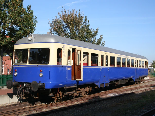 Historischer Zug der Museumsbahn Kaffkieker in blau-gelbem Design steht auf einem sonnigen Gleis.