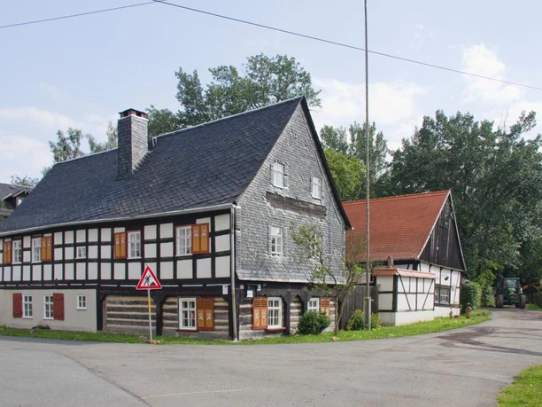 Beim Waldhaus im Greiz-Werdauer Wald Fachwerkhaus mit Holzschindeldach im Greiz-Werdauer Wald an einer ruhigen Straße.