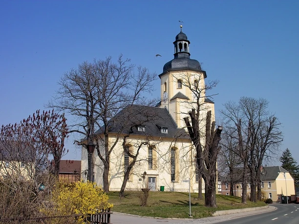 Baroque church in Triebes with a striking onion dome surrounded by bare trees.