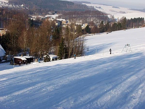 image Schneebedeckte Skipiste mit Liften und Bäumen im Hintergrund einer winterlichen Landschaft.