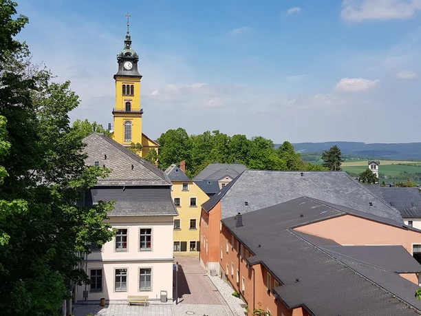 View of Augustusburg's old town with St. Peter's Church surrounded by green countryside.