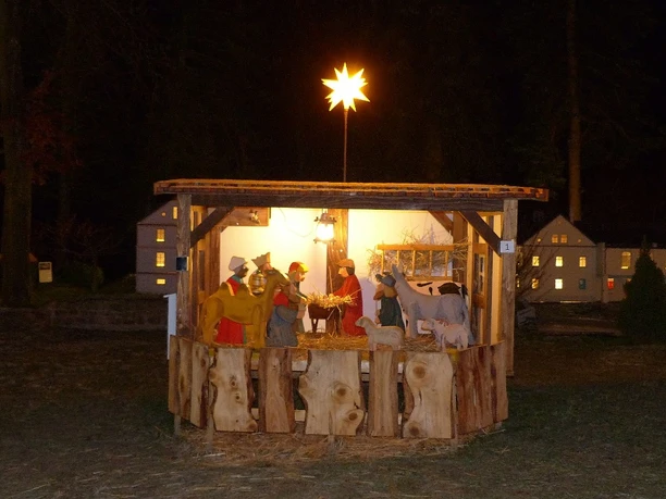 Weihnachtskrippe in Mini-Weißbach Weihnachtskrippe mit leuchtendem Stern, traditionelle Figuren aus Holz.