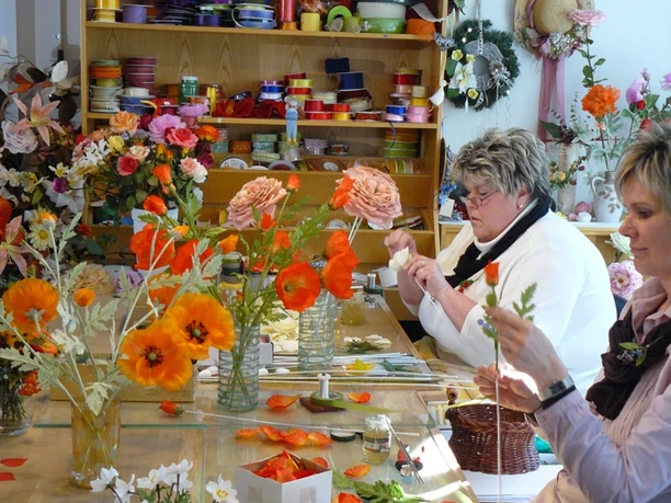 Schaumanufaktur (c) Große Kreisstadt Sebnitz Abteilung Tourismus und Stadtmarketing Personen gestalten Blumenarrangements in einer Manufaktur mit farbenfrohen Dekorationen.