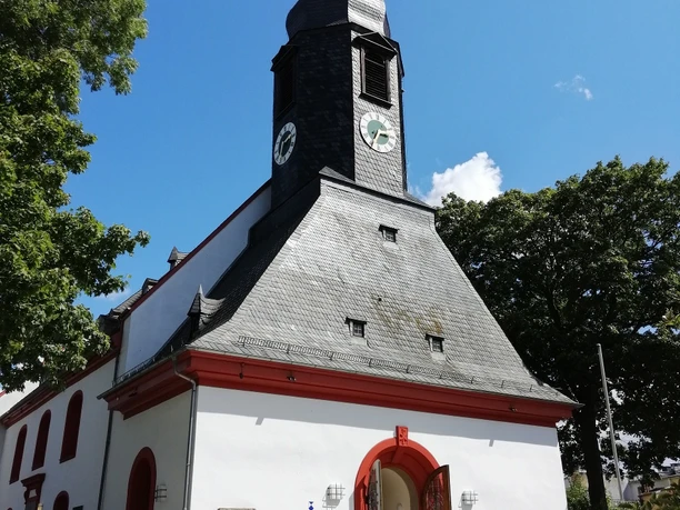 Lorenzkirche - Haupteingang Gotische Kirche mit markantem Turm, Uhr und Haupteingang mit roten Torbögen bei Sonnenlicht.