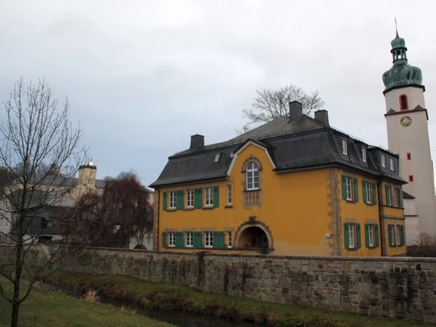 Pfarrhaus und St. Jakobuskirche Oberkotzau Pfarrhaus mit gelber Fassade und St. Jakobuskirche in Oberkotzau im Hintergrund.