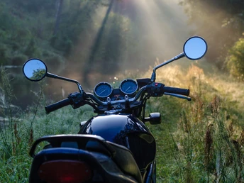 Mottorradtour Motorrad im Vordergrund auf einem schmalen Waldweg, Sonnenstrahlen durchbrechen das Blätterdach.Motorcycle in the foreground on a narrow forest path, sunbeams breaking through the canopy.Motorka v popředí na úzké lesní cestě, sluneční paprsky se prodírají korunami stromů.Motocykl na pierwszym planie na wąskiej leśnej ścieżce, promienie słońca przebijające się przez koronę drzew.Motorfiets op de voorgrond op een smal bospad, zonnestralen breken door het bladerdak.Moto in primo piano su uno stretto sentiero forestale, raggi di sole che attraversano la chioma.