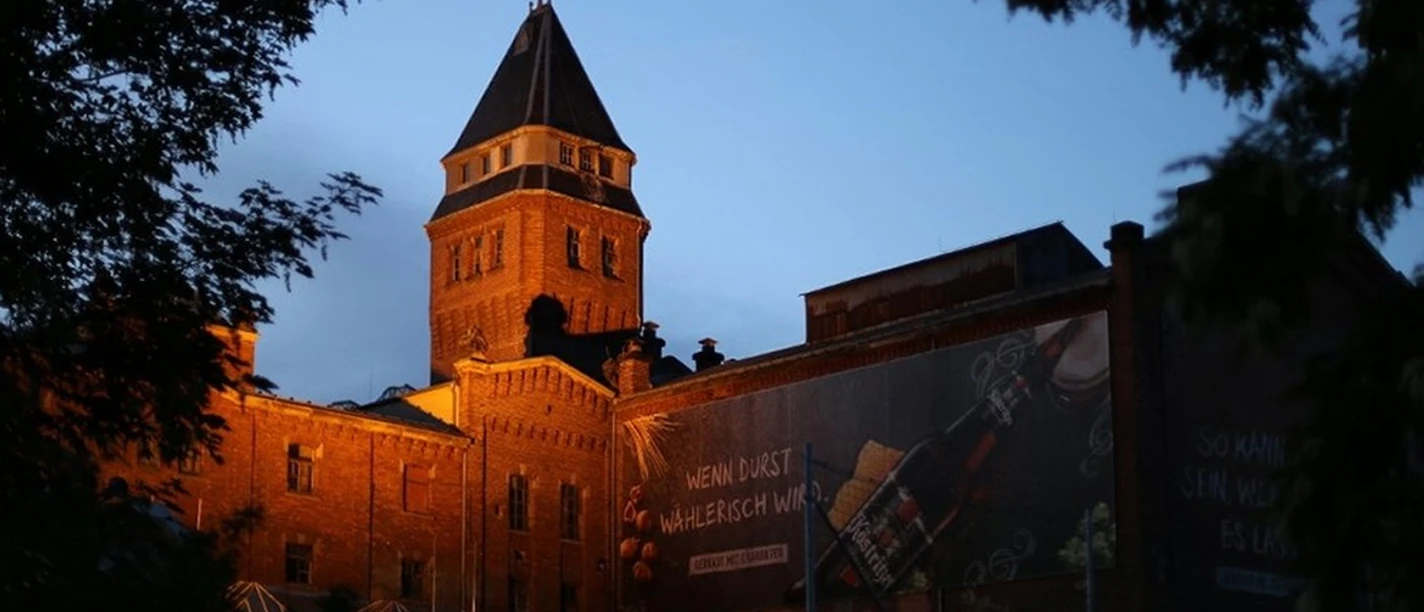 Köstritzer Brauerei Gutshof Köstritzer Brauerei Gutshof bei Abenddämmerung mit beleuchtetem Backsteinturm und Werbebanner.