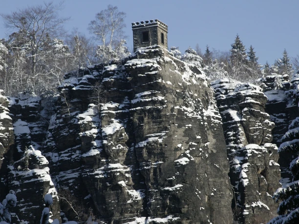 Na strmé zasněžené skále se tyčí hradní věž pevnosti Kaiser Wilhelm.