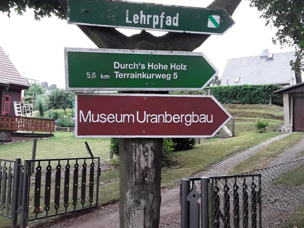 image Wegweiser aus Holz mit Richtungsschildern zu einem Lehrpfad und dem Museum Uranbergbau.
