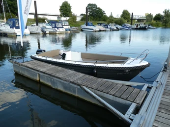 Bootsvermietung im Uesener Weserhafen Boot im Uesener Weserhafen, festgemacht an einem Steg, umgeben von weiteren Booten und grüner Landschaft.