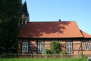 Historisches Fachwerkgebäude mit Glockenturm, roten Dachziegeln und weißen Sprossenfenstern.