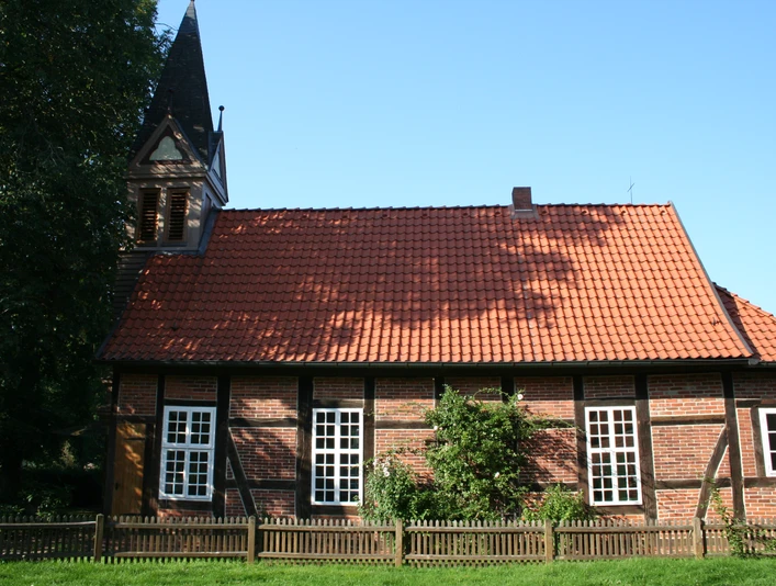 Fachwerkkapelle Anderten Historisches Fachwerkgebäude mit Glockenturm, roten Dachziegeln und weißen Sprossenfenstern.