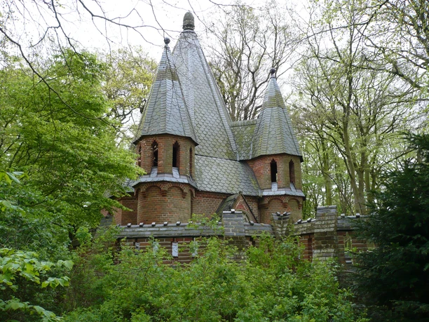 Mausoleum im Etelser Schlosspark Backsteingebäude mit spitzen Türmen umgeben von dichtem Grün im Etelser Schlosspark.