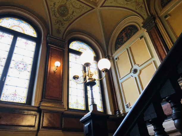 Historisch trappenhuis met prachtige glas-in-loodramen, sierlijk stucwerk en elegante houten trap.