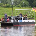 Weserfähre transportiert Personen und Fahrräder über einen ruhigen Fluss vor grüner Landschaft.