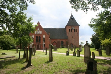 St.-Sigismund-Kirche in Daverden St.-Sigismund-Kirche in Daverden, Backsteingotik mit Friedhof, umgeben von Bäumen, unter blauem Himmel.