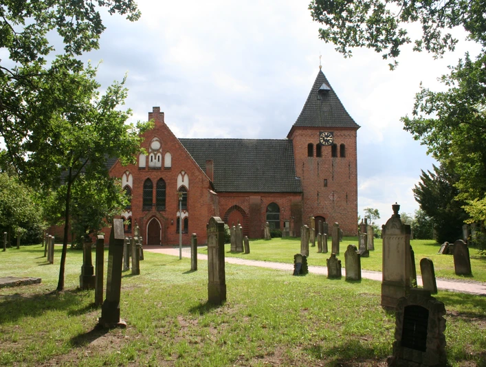 St.-Sigismund-Kirche in Daverden St.-Sigismund-Kirche in Daverden, Backsteingotik mit Friedhof, umgeben von Bäumen, unter blauem Himmel.