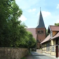 St. Laurentius-Kirche Liebenau Straße führt zu einer historischen Backsteinkirche mit spitzem Turm, flankiert von Fachwerkhäusern.